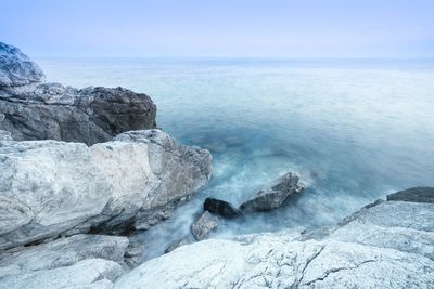 Scenic view of rocks in sea against blue sky