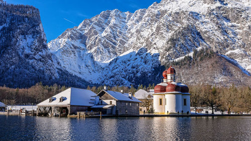 Panoramic shot of building and snowcapped mountains against sky