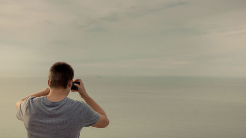 Side view of woman standing at beach against sky