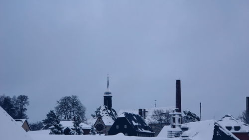 Snow covered houses and buildings against sky