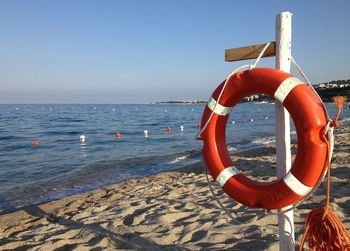 Life belt hanging at beach against clear blue sky