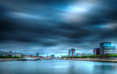 City with river against cloudy sky