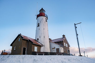 Low angle view of lighthouse by building against sky