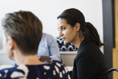 Businesswoman looking at colleague during meeting in board room