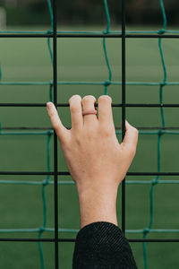 Cropped image of hand holding metal against wall