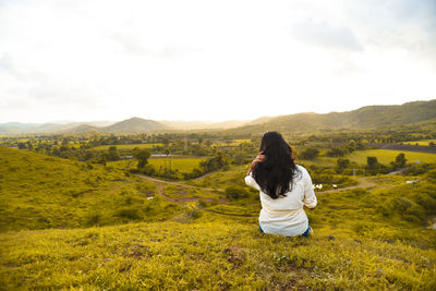 Rear view of woman looking at landscape against sky