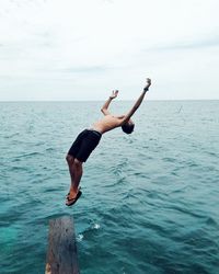 Full length of woman jumping on sea against sky