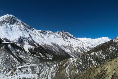 Snowcapped mountains against clear blue sky