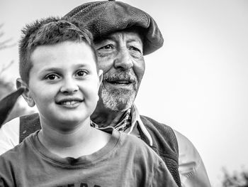 Portrait of smiling boy with grandfather against clear sky