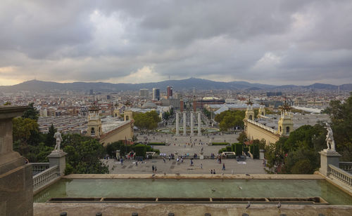 High angle view of city buildings against cloudy sky