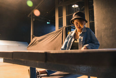 Young man looking away while sitting on illuminated stage