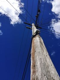 Low angle view of telephone pole against blue sky