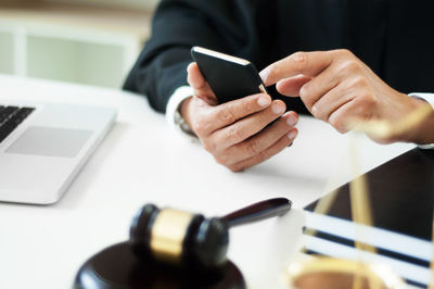 Midsection of man using smart phone on table