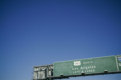 Low angle view of information sign against clear blue sky