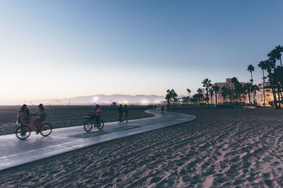 People riding bicycle on road against clear sky