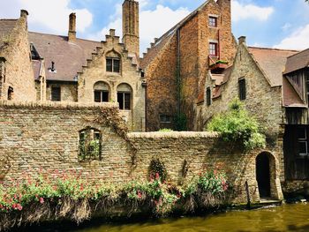 Old building by canal against sky