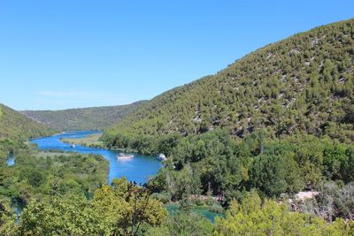 Scenic view of lake and mountains against clear blue sky