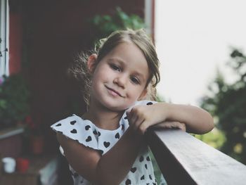 Portrait of cute smiling girl standing on balcony