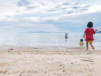 Boy standing on beach against sky