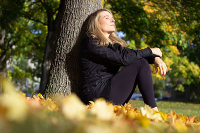 Young woman sitting on tree trunk