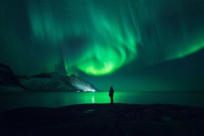 Man standing on mountain against sky at night during winter