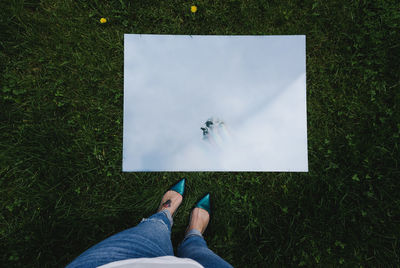 Low section of woman standing by mirror on lawn