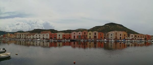 Sailboats moored in city by buildings against sky