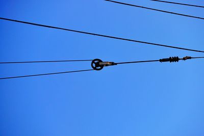 Low angle view of pulley and cables against clear sky