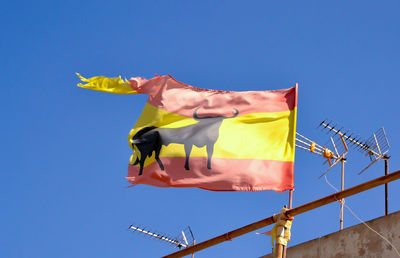 Low angle view of flags against clear blue sky