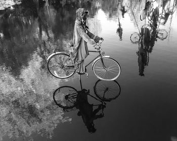 Reflection of person riding bicycle in water