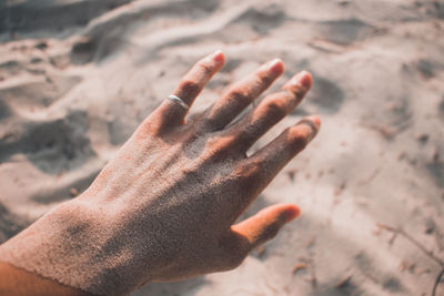 Close-up of hand covered with sand