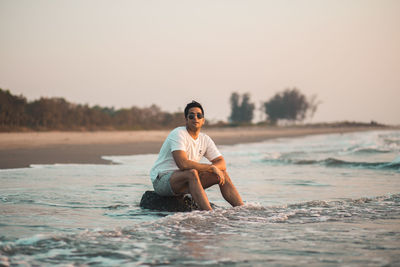 Full length of young man sitting on beach