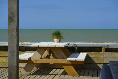 Chairs and table by sea against sky