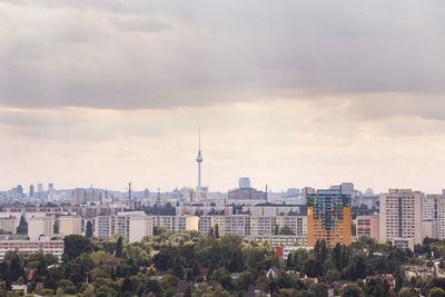 Fernsehturm amidst city against cloudy sky