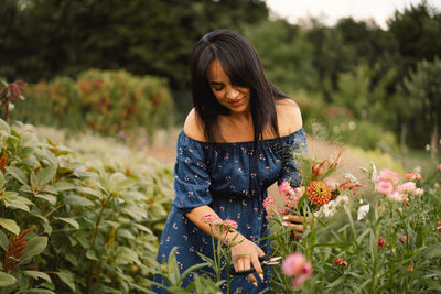 Young woman touching flowers at park