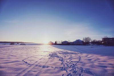 Scenic view of snow covered field against sky during sunset