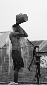 Rear view of woman holding umbrella against clear sky