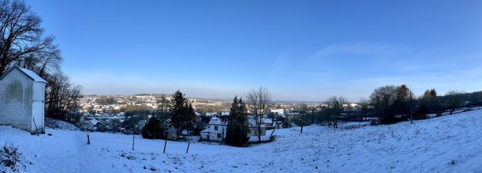 Panoramic view of trees and buildings against sky during winter