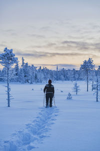 Rear view of people on snow covered field against sky