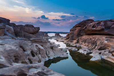 Rock formations in sea against sky during sunset