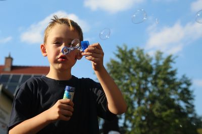 Close-up of boy blowing bubbles outdoors