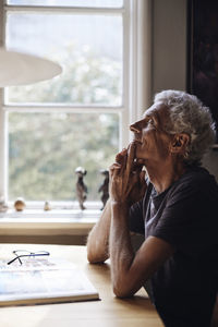 Side view of young man using mobile phone at home