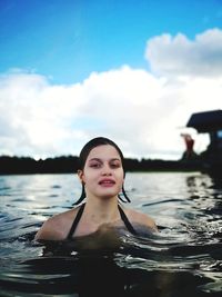 Portrait of girl swimming in lake against cloudy sky