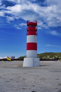 Lighthouse on beach against sky