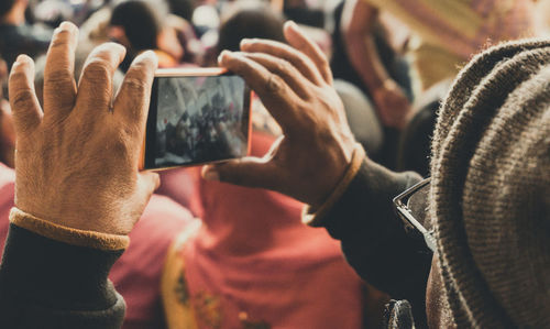 Close-up of old man photographing with mobile phone