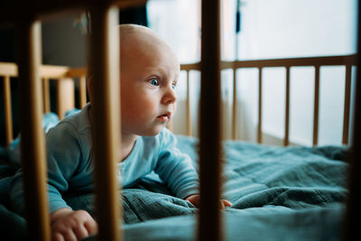 Baby boy toddler crawling in crib at kids nursery room at home. looking and smiling at the camera