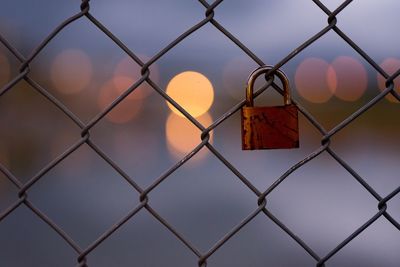 Close-up of padlock hanging on chainlink fence