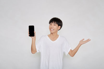 Portrait of smiling young man using smart phone against white background