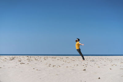 Young man with arms outstretched on beach