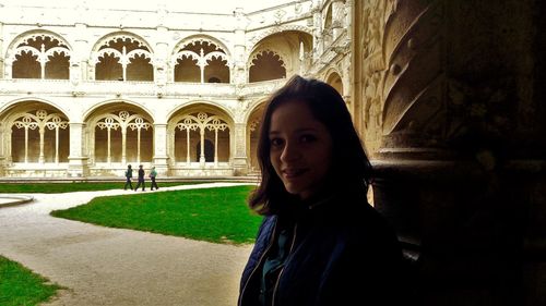 Portrait of young woman standing in historic building